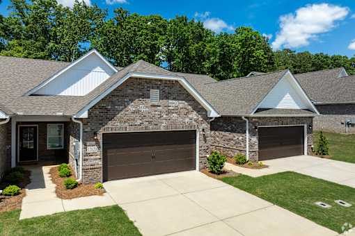 A house with a brown garage door and a stone wall.