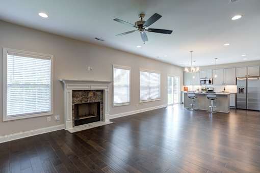 A spacious living room with a fireplace and a kitchen in the background.