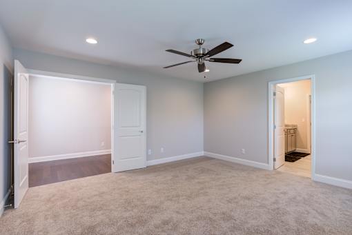 A room with a ceiling fan and carpeted floor.
