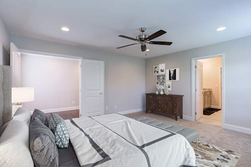 A bedroom with a bed, dresser, and ceiling fan.