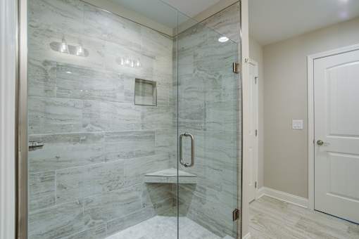 A bathroom with a walk-in shower and a white door.