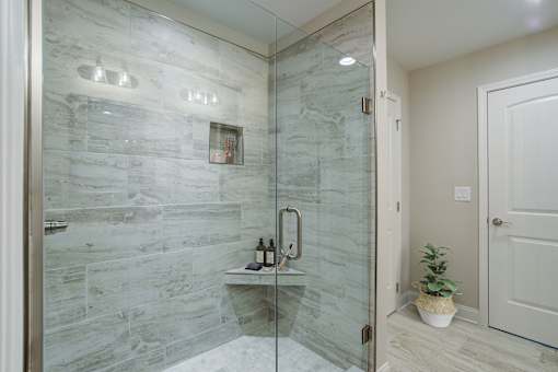 A bathroom with a walk-in shower and a white door.