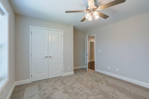 A room with a ceiling fan and carpeted floor.