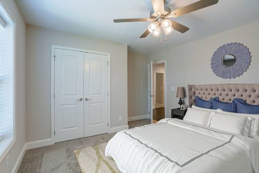 A bedroom with a white bed and a ceiling fan.