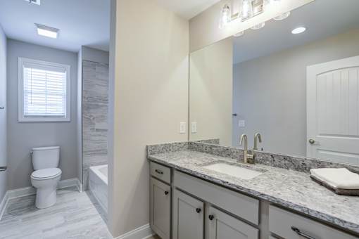 A bathroom with a granite countertop and a white toilet.