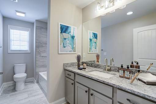 A bathroom with a toilet, sink, and mirror.