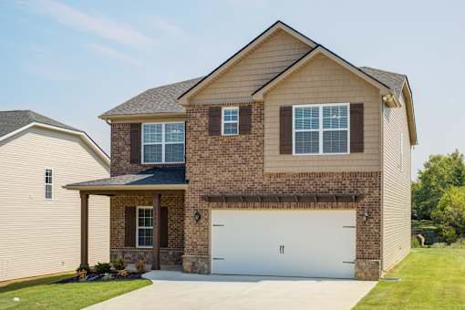 A two-story house with a garage door and a covered porch.