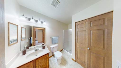 A bathroom with a toilet, sink, mirrors and a wooden door.