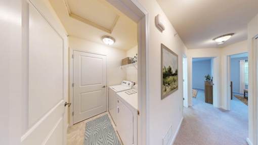 A hallway with a white door and a painting on the wall.