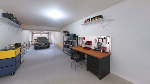 A garage with a workbench and a car in the background.