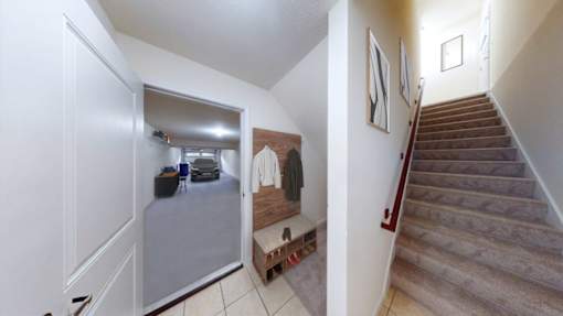A hallway with a staircase and a bench.