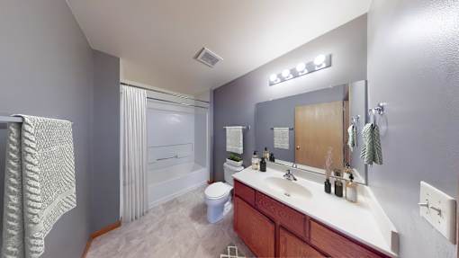 A bathroom with a toilet, sink, and mirror.