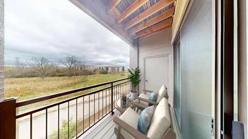 A balcony with a couch and a potted plant overlooking a field.