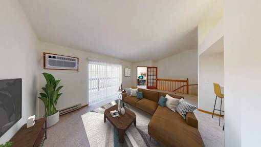 A living room with a brown couch and a television on the wall.