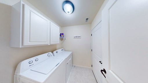A white washing machine is in a small laundry room.