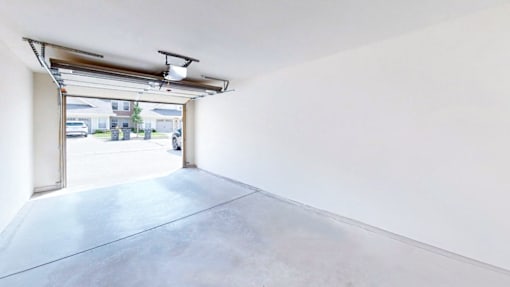 A white room with a concrete floor and a large open door.