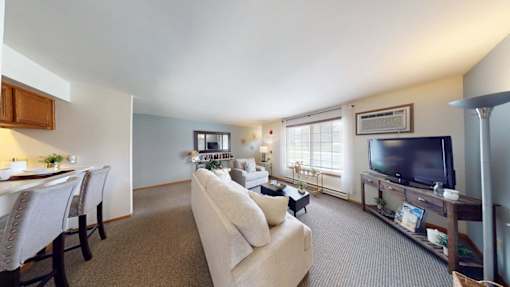 A living room with a couch, a television, and a dining table.
