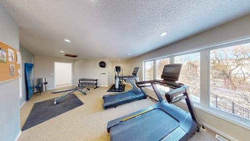 A spacious home gym with a treadmill, exercise bike, and other equipment.