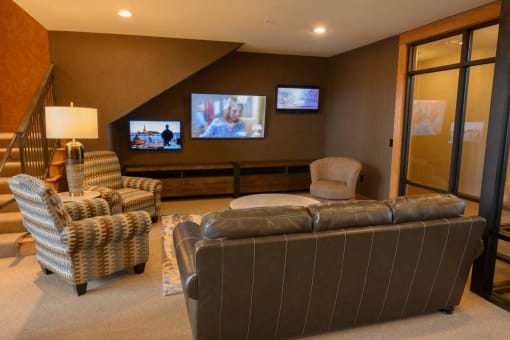 a living room with couches and chairs and televisions