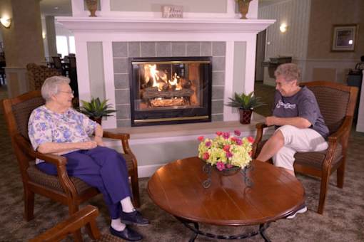 two people sitting around a table in front of a fireplace