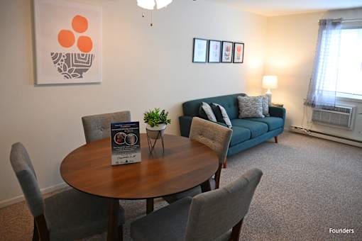 A living room with a grey couch, a brown table, and a painting on the wall.