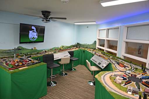 A room with a table, chairs, and a model train set.