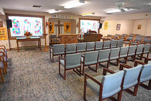 A church interior with rows of chairs and a sign that says "Thank You Jesus for Life".