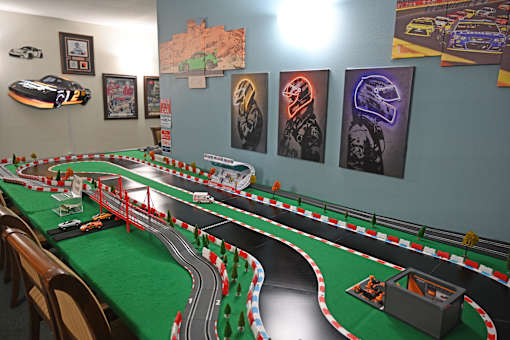 A table with a green tablecloth has a toy race track on it.
