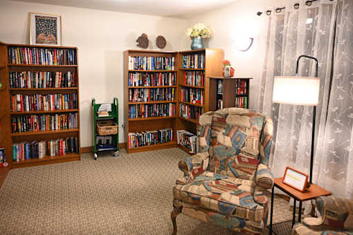 A room with a chair and a bookshelf filled with books.