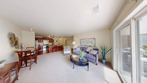 A living room with a couch, coffee table, and a dining table.