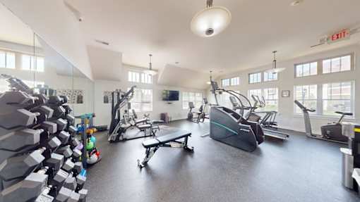 A gym with a variety of equipment including treadmills, weights, and exercise machines.