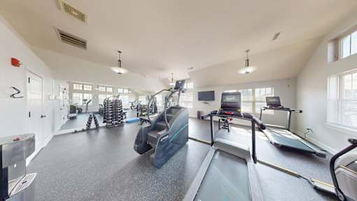 A gym with treadmills, elliptical machines, and other exercise equipment.