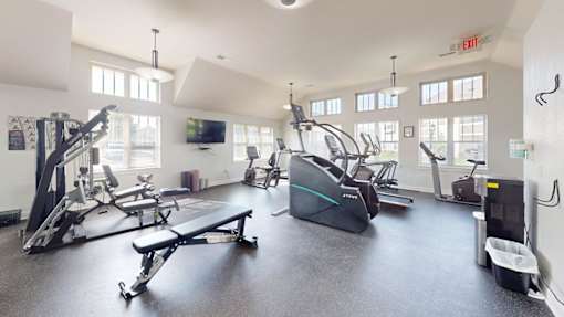 A gym with a variety of exercise equipment including treadmills, stationary bikes, and weight machines.