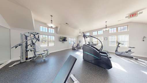 A gym with a row of exercise bikes and a treadmill.