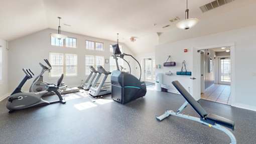 A spacious gym with a variety of equipment including treadmills, stationary bikes, and weight machines.