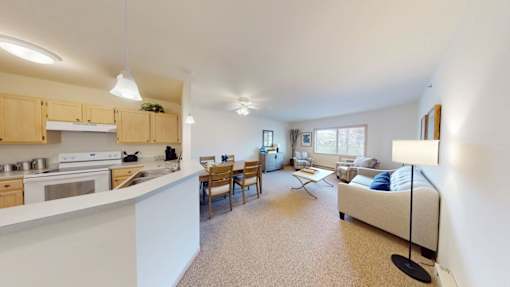 A well-lit, spacious kitchen and living room with a dining table and chairs.