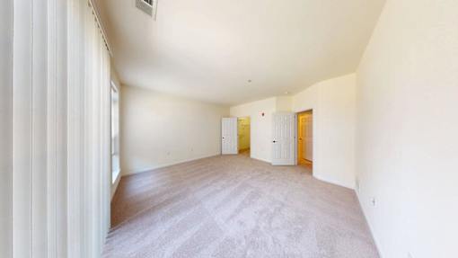 A room with a carpeted floor and two doors.