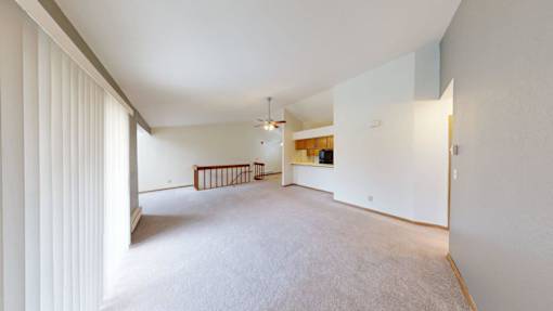 A large, empty room with a wooden bench and a ceiling fan.