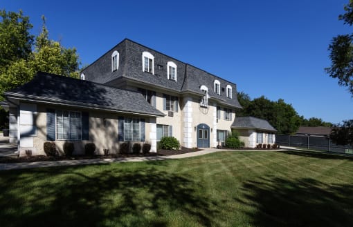 a white house with a gray roof and a green lawn