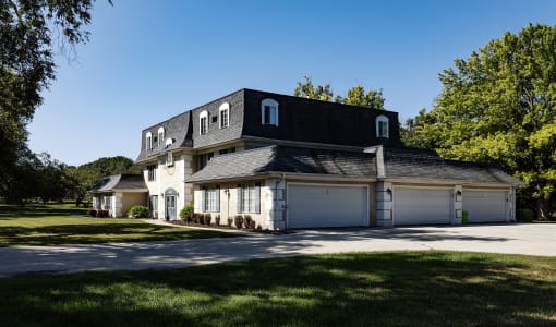 a white house with a black roof and white garage doors