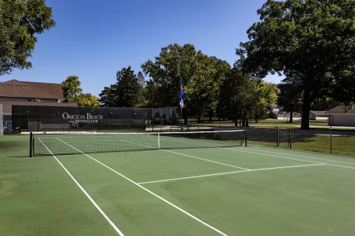 a tennis court in front of a building with trees