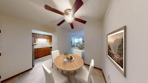 A dining room with a table set for two and a painting on the wall.