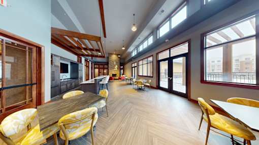 A long wooden table with yellow chairs is in a room with a lot of windows.