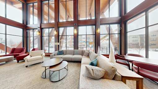 A large room with a long couch and a table in front of a large window.