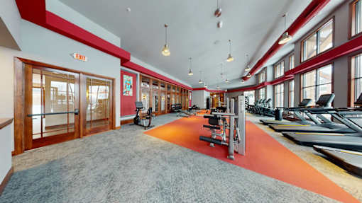 A gym with a row of treadmills and exercise bikes.