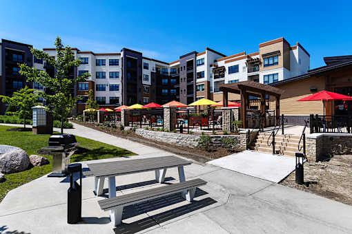 A park area with a bench and a fire hydrant in front of apartment buildings.