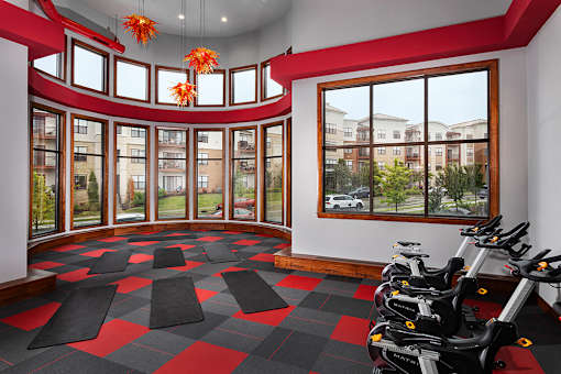 A gym with a row of stationary bikes and a checkered floor.