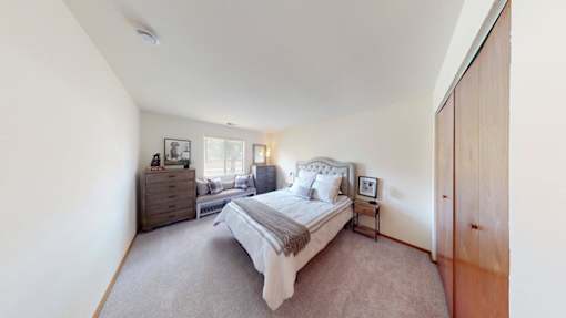A bedroom with a large bed, a dresser, and a nightstand.