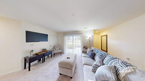 A living room with a grey couch and a television on the wall.