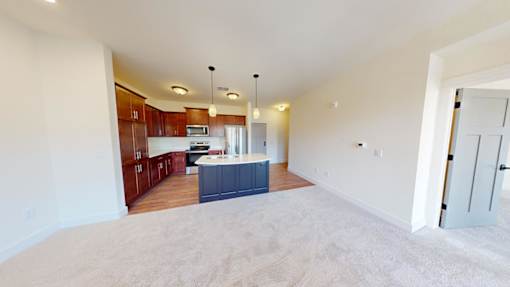 A spacious living room with a kitchen in the background.